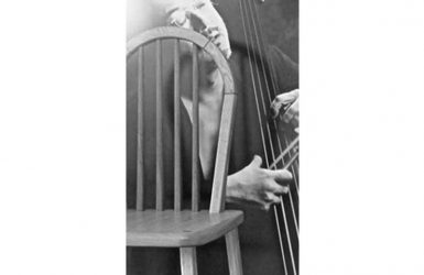 ハープの形の背もたれの椅子とベースを弾いている人の写真